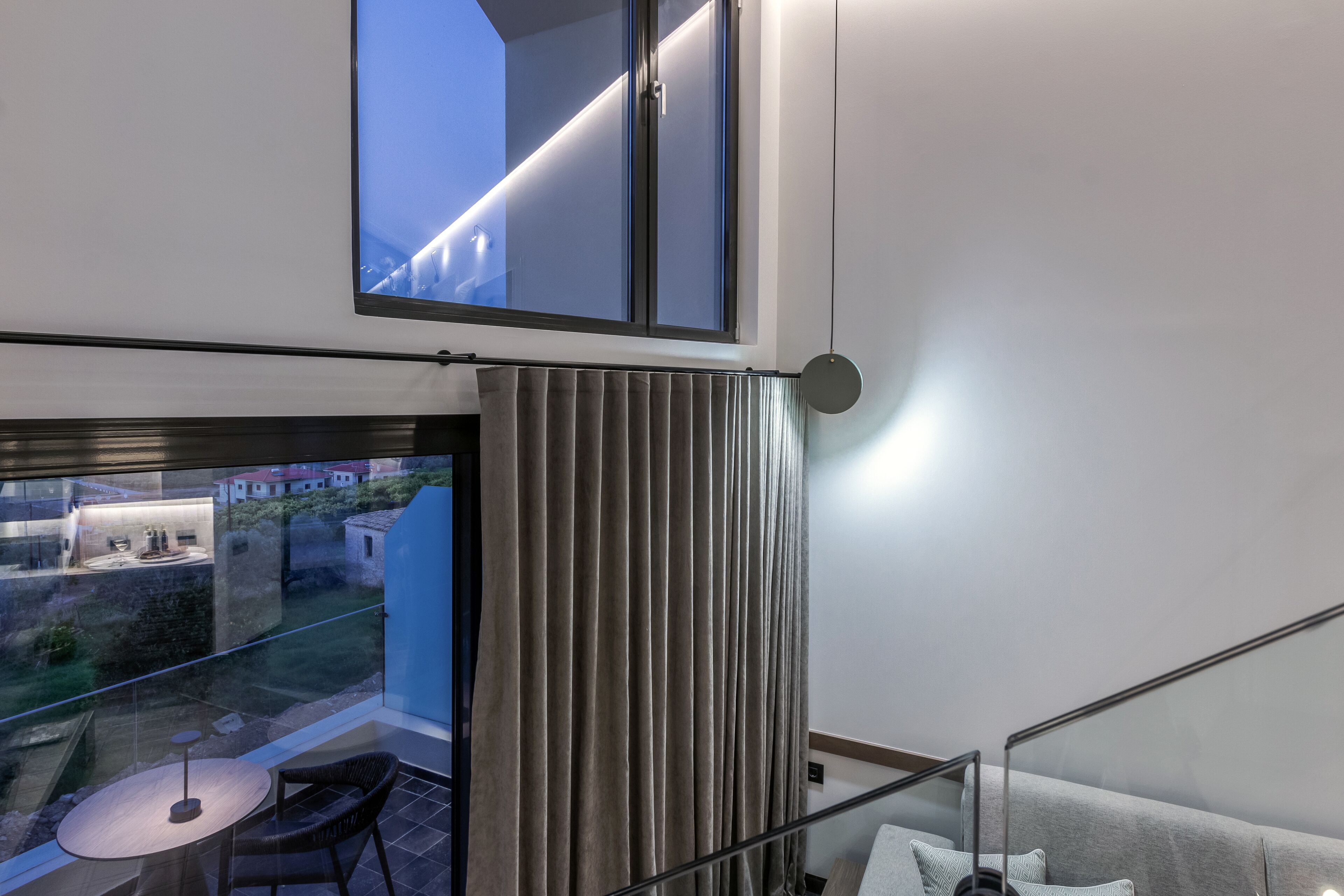 Una habitación moderna con balcón, una mesa con sillas y un sofá.