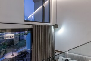 Una habitación moderna con balcón, una mesa con sillas y un sofá.