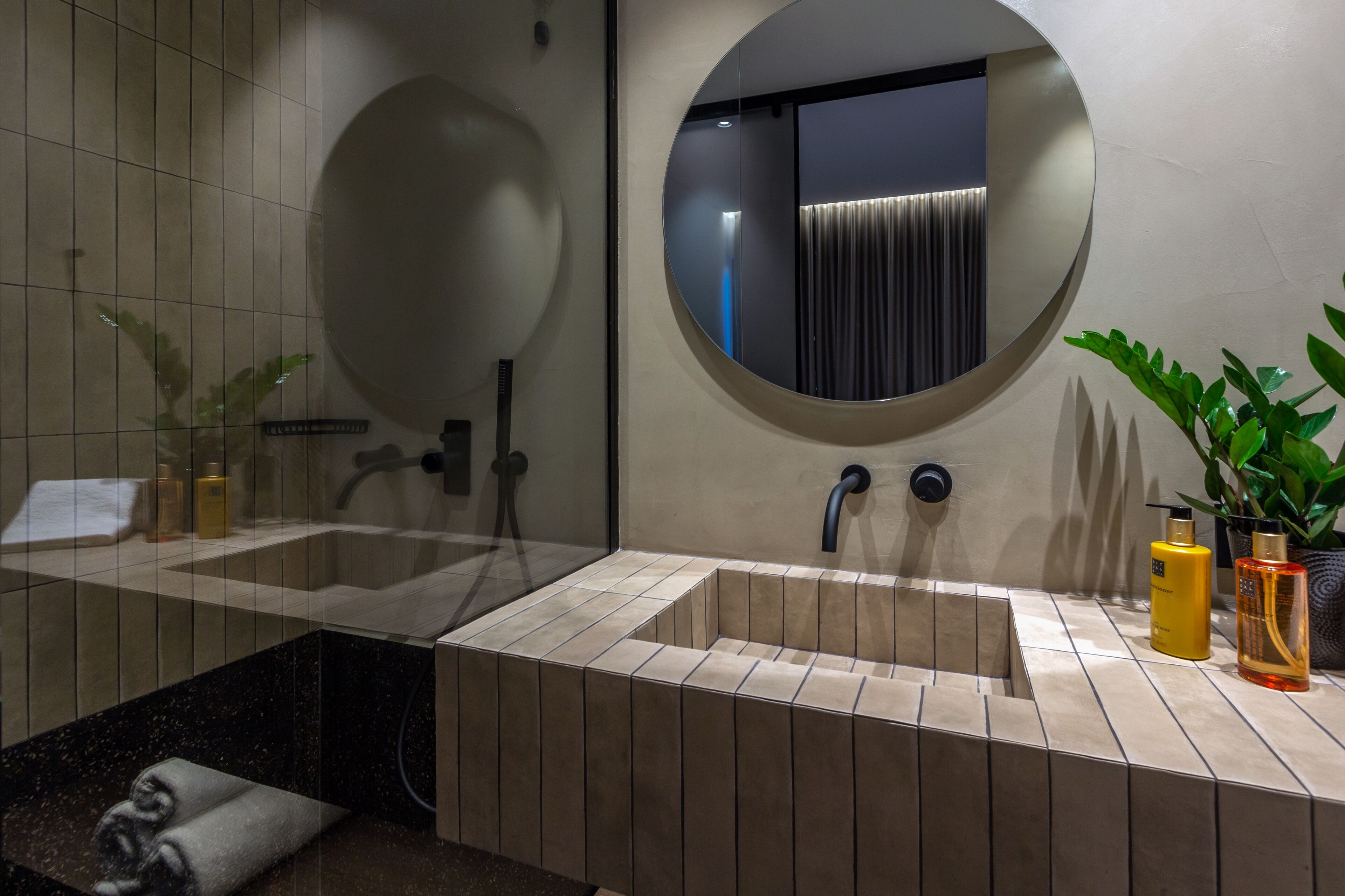 A modern bathroom with a large mirror, two sinks, and a bathtub.