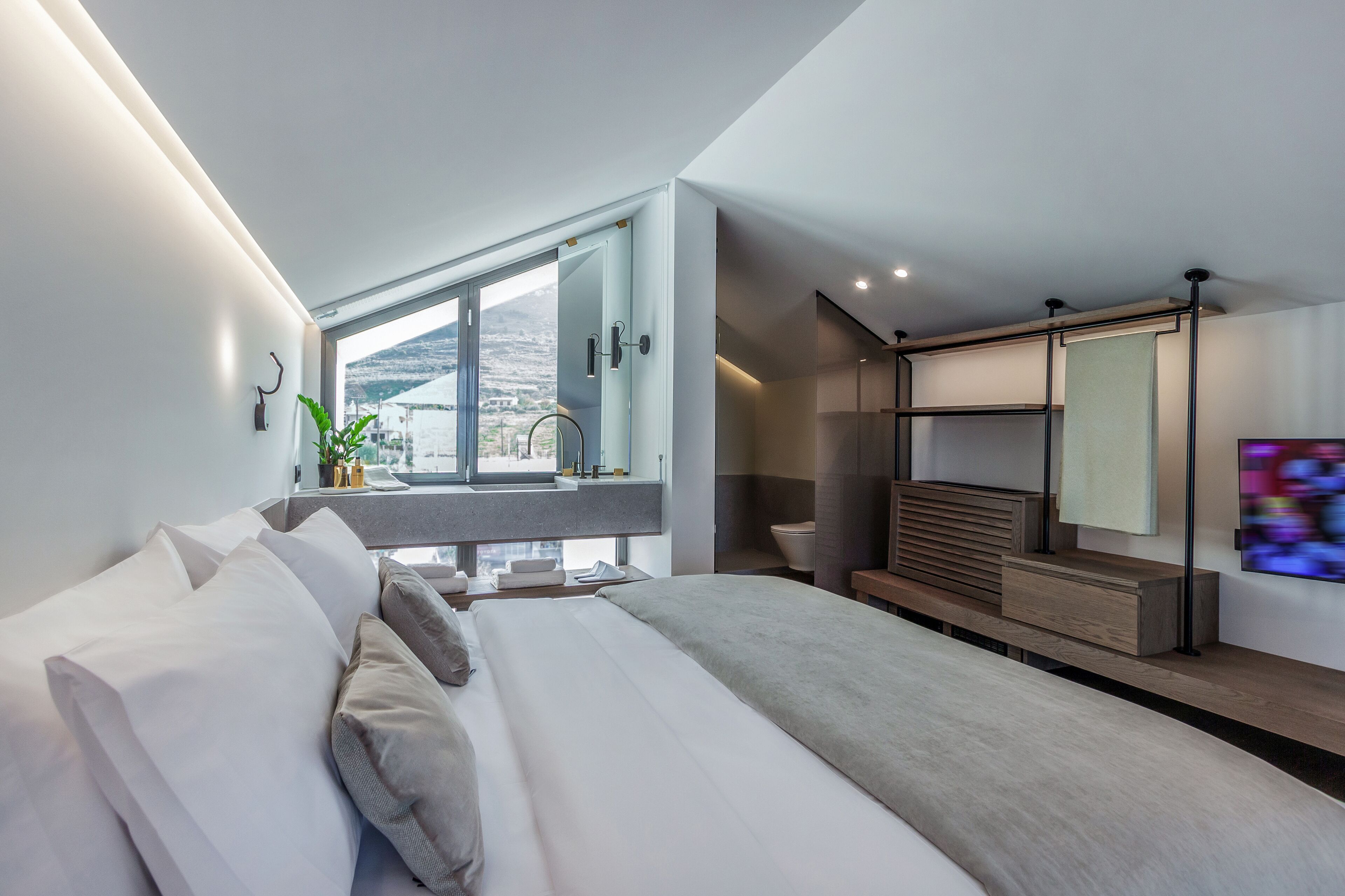 Une chambre moderne dotée d’un grand lit, d’un bureau intégré, d’une salle de bain et offrant une vue sur la ville.