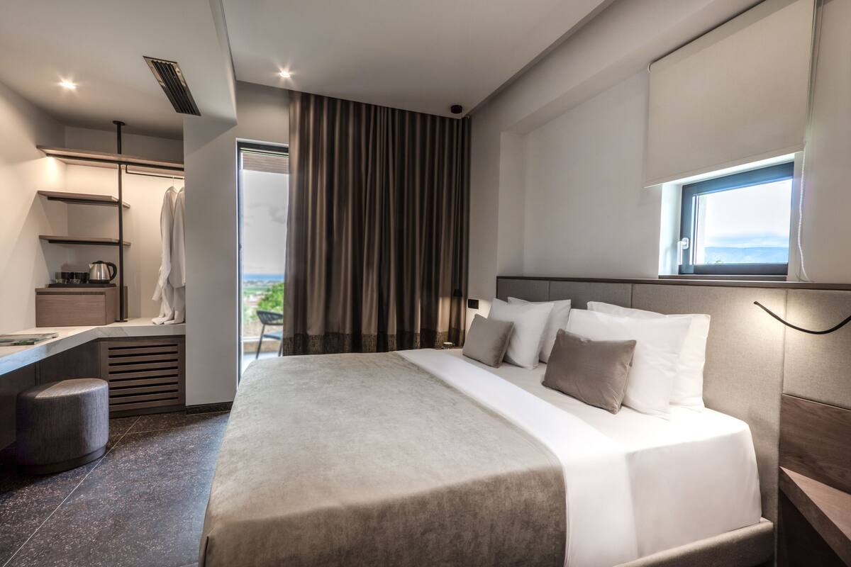 Una habitación de hotel moderna con una cama grande, un escritorio y vistas al exterior.