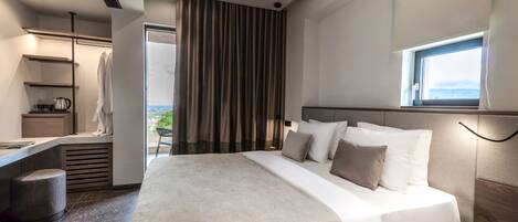 A modern hotel room with a large bed, a desk, and a view of the outdoors.