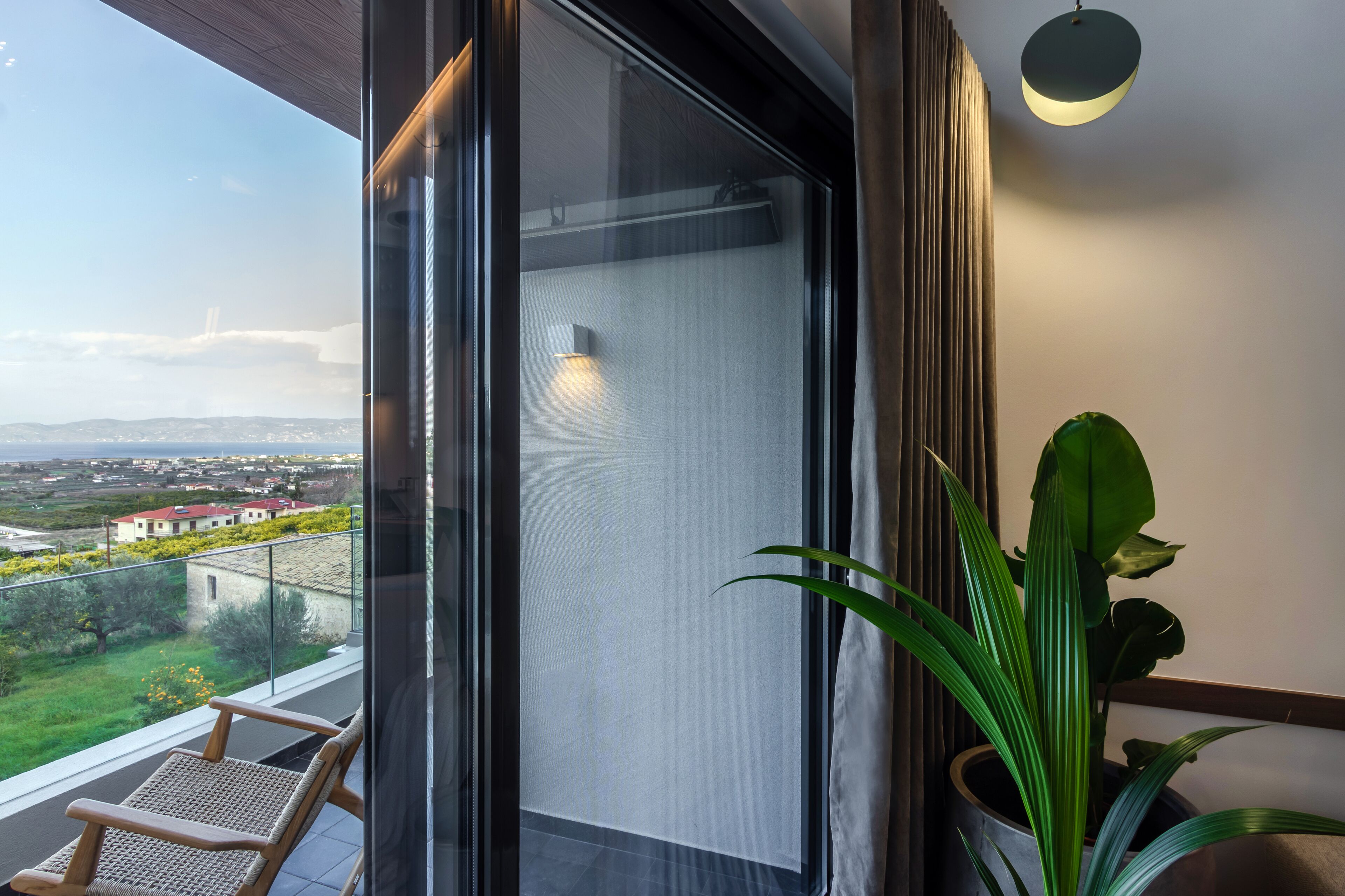 Een balkon met uitzicht op een landschap, een bloempot en een stoel.