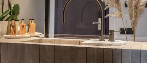 A modern bathroom with a large mirror, a gold faucet, and a wooden vanity.
