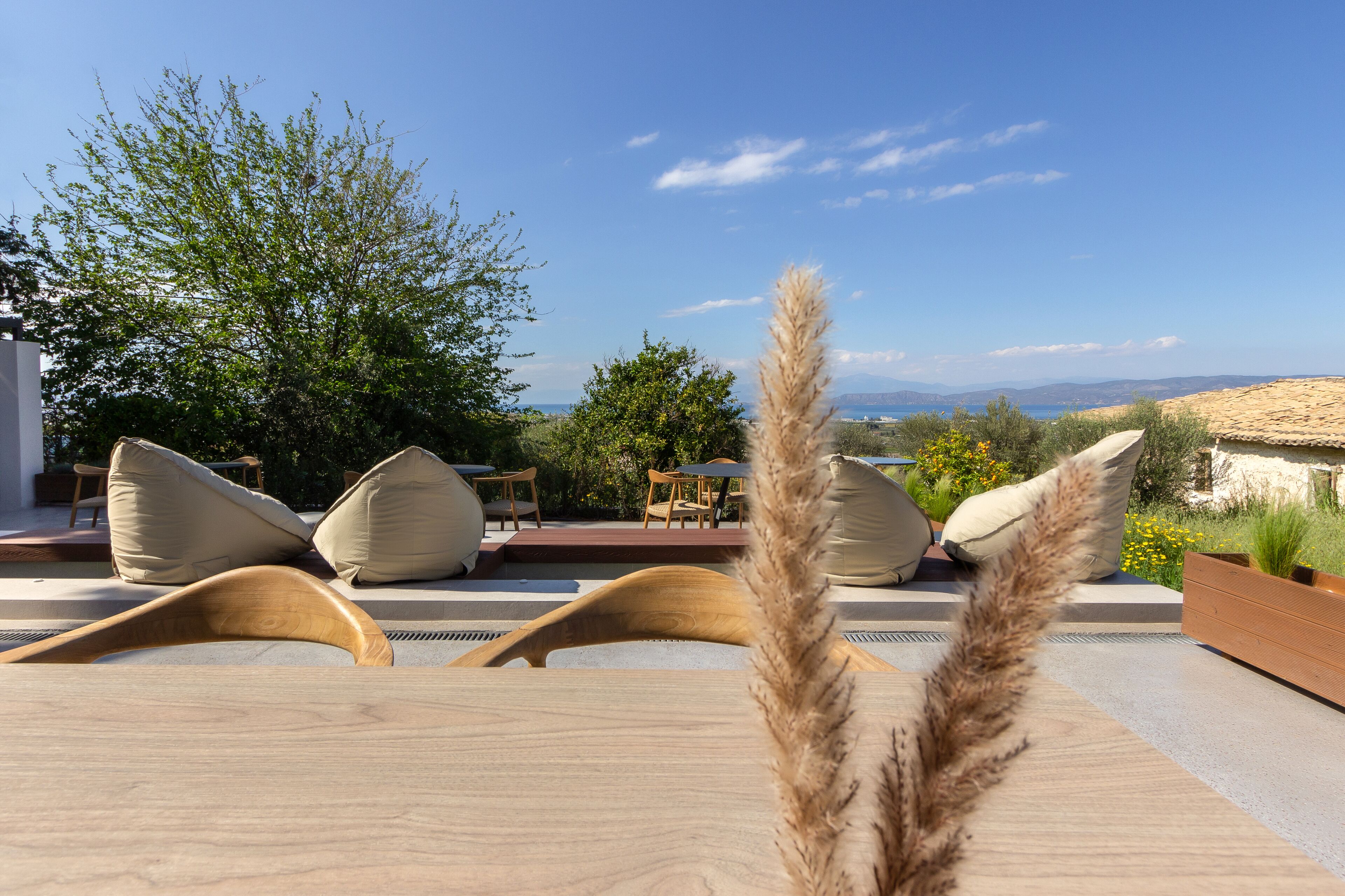 A terrace with wooden lounge chairs and a view of the sea.