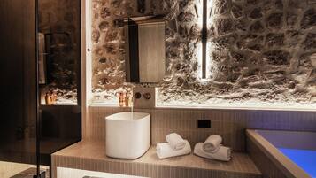 Une salle de bain moderne avec un mur en pierre, un grand lavabo et une baignoire.