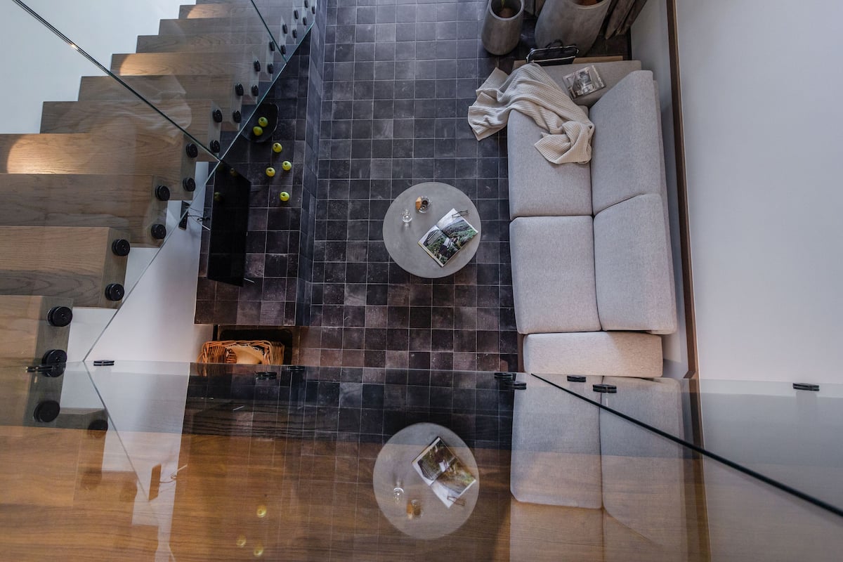 Un interior moderno con una escalera, un sofá y dos mesas redondas.