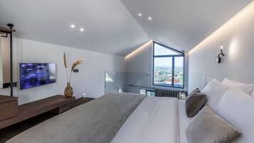 Une chambre moderne dotée d’un grand lit, d’une télévision, d’une fenêtre donnant sur la ville et d’un design minimaliste.