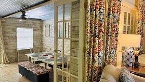 A cozy room with a wooden interior, a dining table with chairs, a sofa, and a patterned curtain. - The Retreat - Entire Residential Home! (Daphne)