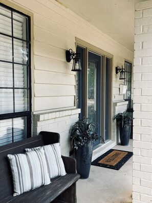 A porch with a bench, potted plants, and a welcome mat. - The Retreat - Entire Residential Home! (Daphne)