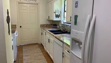 A kitchen with white cabinets, a granite countertop, a built-in oven, and a refrigerator.