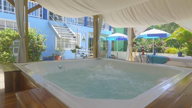 A hot tub under a white canopy, surrounded by potted plants and a blue building with stairs. - Hotel Boutique Royal Palm Inn (San Andrés)