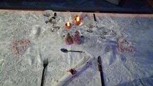 A table set with a white lace tablecloth, a candle, and a small vase with flowers. - Hotel Boutique Royal Palm Inn (San Andrés)