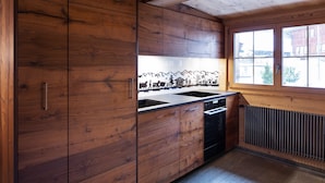 Una cocina con armarios de madera, un lavamanos doble y una ventana con vistas a un paisaje montañoso.