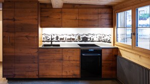 Una cocina con armarios de madera, lavavajillas y ventana con vistas al exterior.