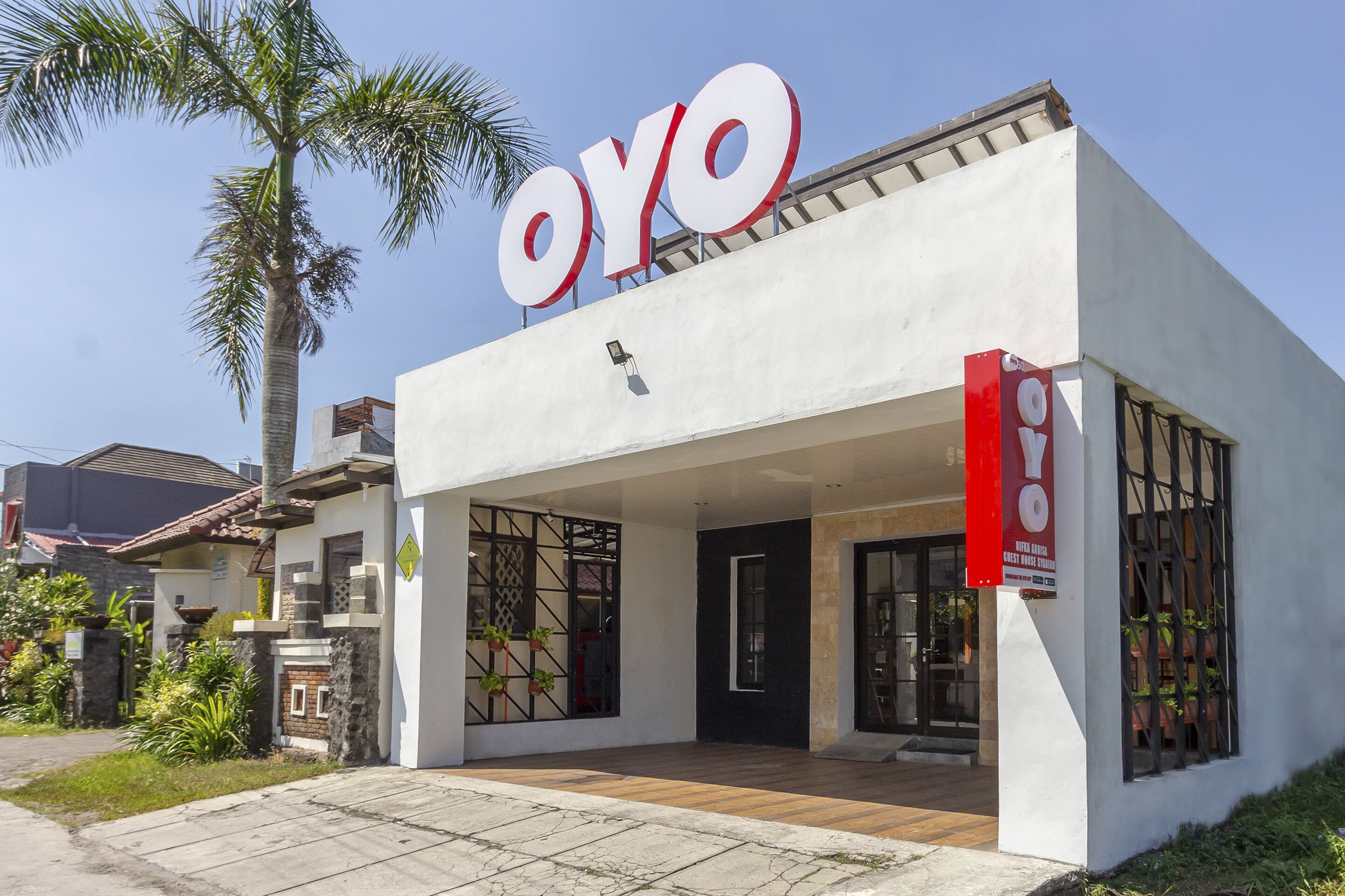 Un edificio moderno con un llamativo letrero 'OYO', amplias ventanas y un área de acceso cubierta.