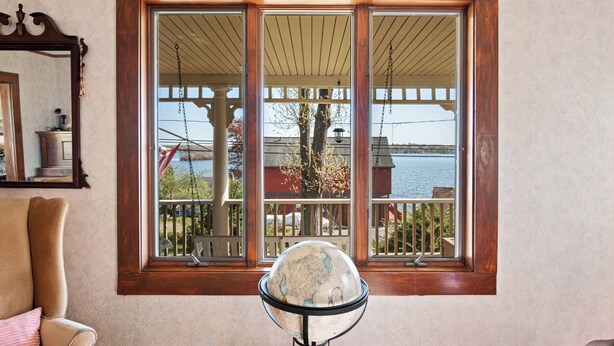 A room with a large window, a globe, a chair, and a wooden floor. - Grammy's Lake House on Lake Pocotopaug (East Hampton)