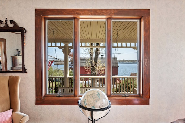A room with a large window, a globe, a chair, and a wooden floor.