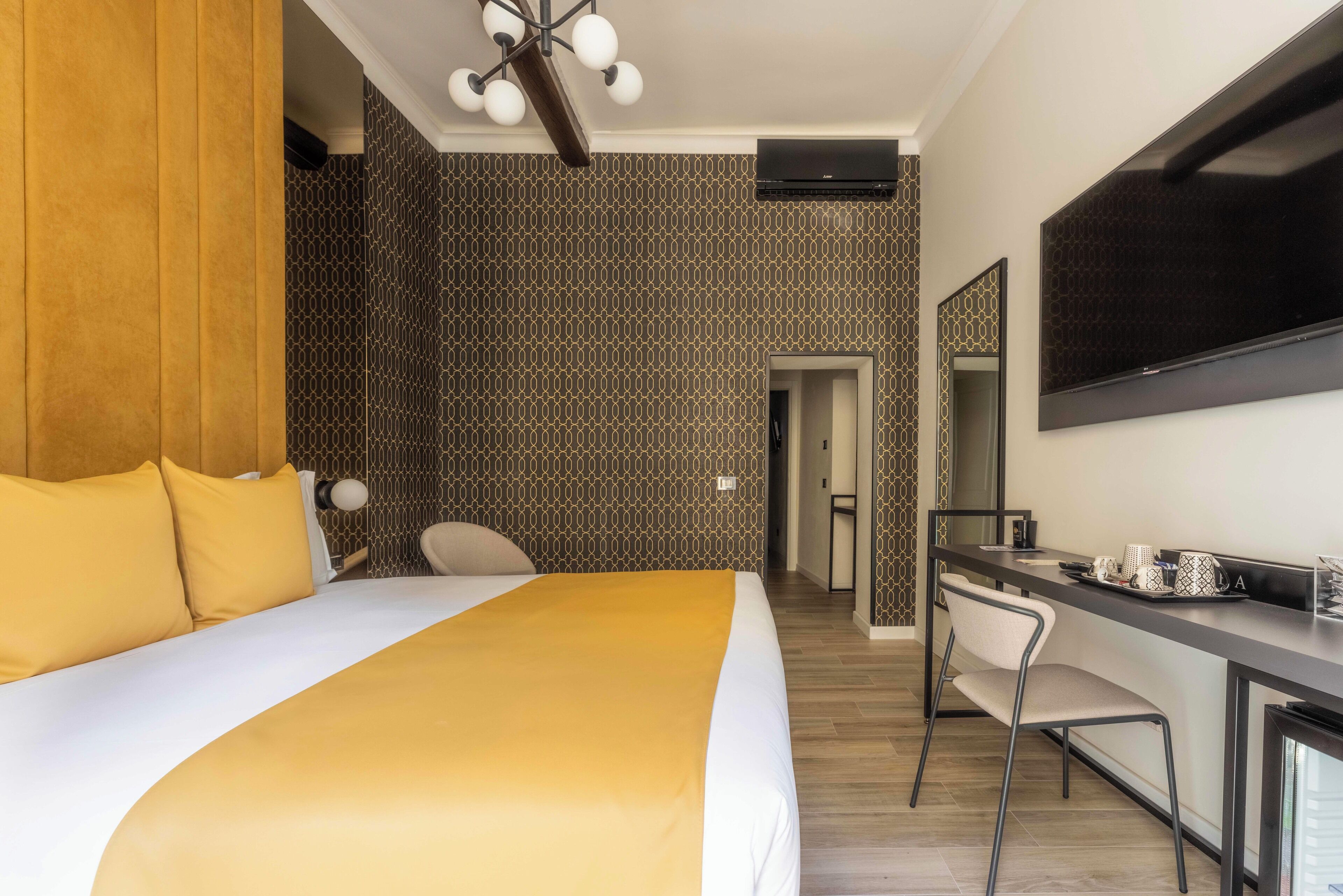 Una habitación de hotel con una cama grande, un escritorio con silla, televisor y espejo.