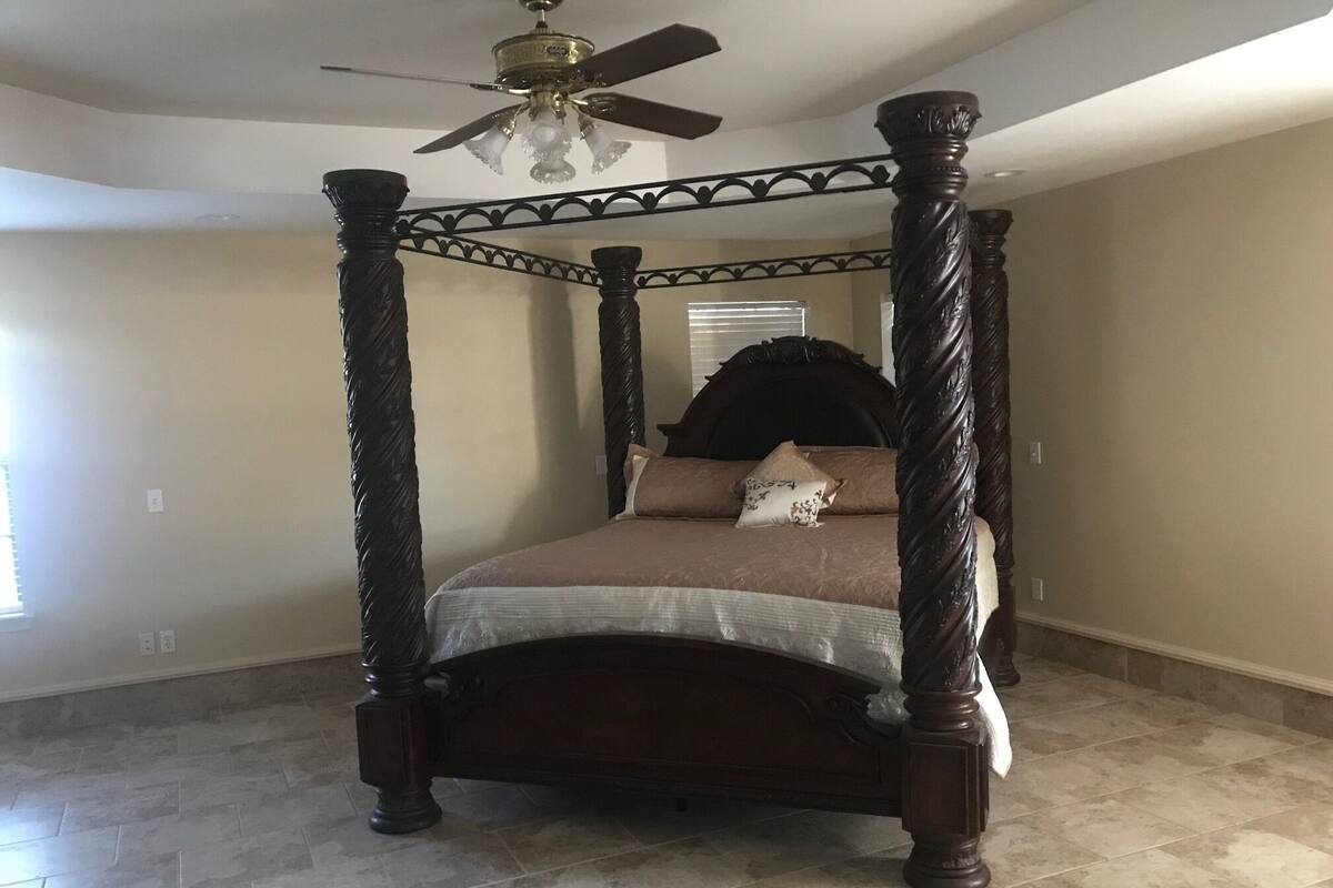 A four-poster bed with a dark wooden frame and a decorative ceiling fan.