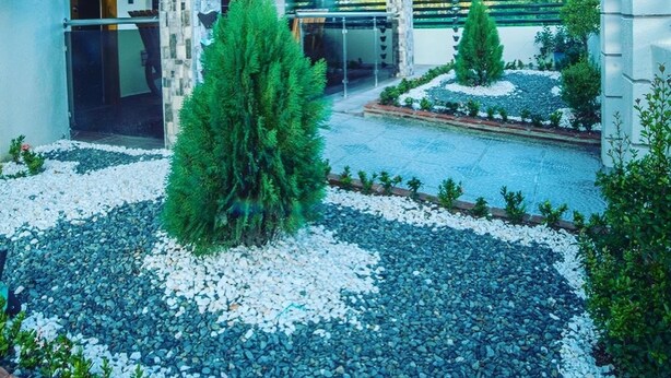 A modern building with a glass entrance, stone pillars, and a landscaped garden with a pool. - Romantic VillaLunaCaridad (Jarabacoa)