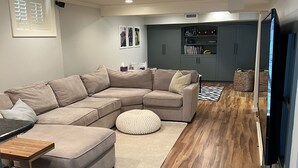 Ein modernes Wohnzimmer mit Ecksofa, Hocker und einem kleinen Tisch.