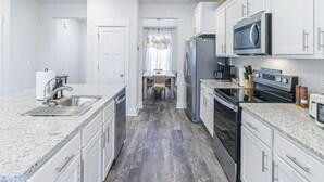Cozinha moderna com bancadas de granito, eletrodomésticos de aço inoxidável e armários brancos.