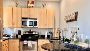 Eine moderne Küche mit Holzausstattung, Edelstahlgeräten, einer Granitarbeitsplatte und einer Spritzschutzwand.