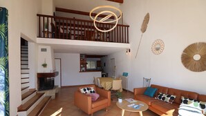 A spacious living area with a staircase, a dining table, and a sofa. - Villa Port Camargue – Private pool, air conditioning, free parking (LE GRAU DU ROI)