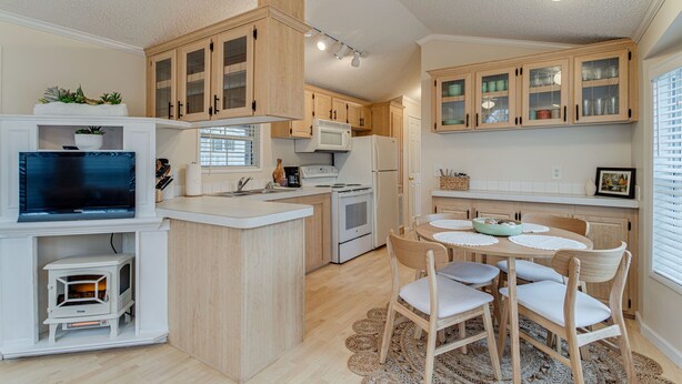 Una cocina compacta con armarios de madera, microondas, estufa y comedor con mesa y sillas.