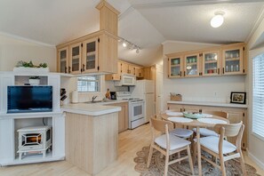 Una cocina compacta con armarios de madera, microondas, estufa y comedor con mesa y sillas.