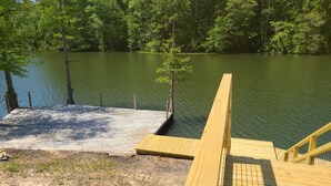Une jetée en bois s’étendant dans un lac, lequel est entouré d’une forêt dense.
