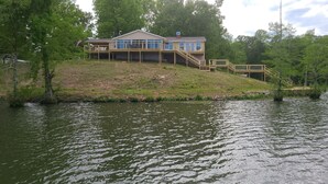Une maison au bord du lac, dotée d’une terrasse et d’un escalier menant à un balcon.