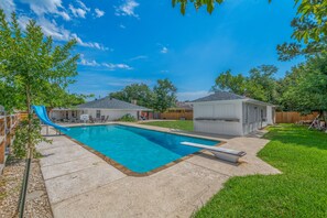 Un patio trasero con piscina, tobogán y un cobertizo pequeño.