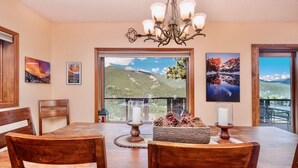 A dining area with a large table, wooden chairs, a chandelier, and framed pictures on the walls. - Divine Destiny Vacation Home at Windcliff (Estes Park)