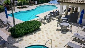 A swimming pool with a small hot tub, surrounded by lounge chairs and umbrellas. - Pelican Sound Golf and River Club (Estero)