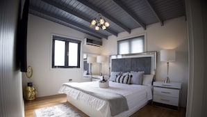 A bedroom with a large bed, bedside tables, a chandelier, and a window. - The Good Vibes House (Cabo Rojo)