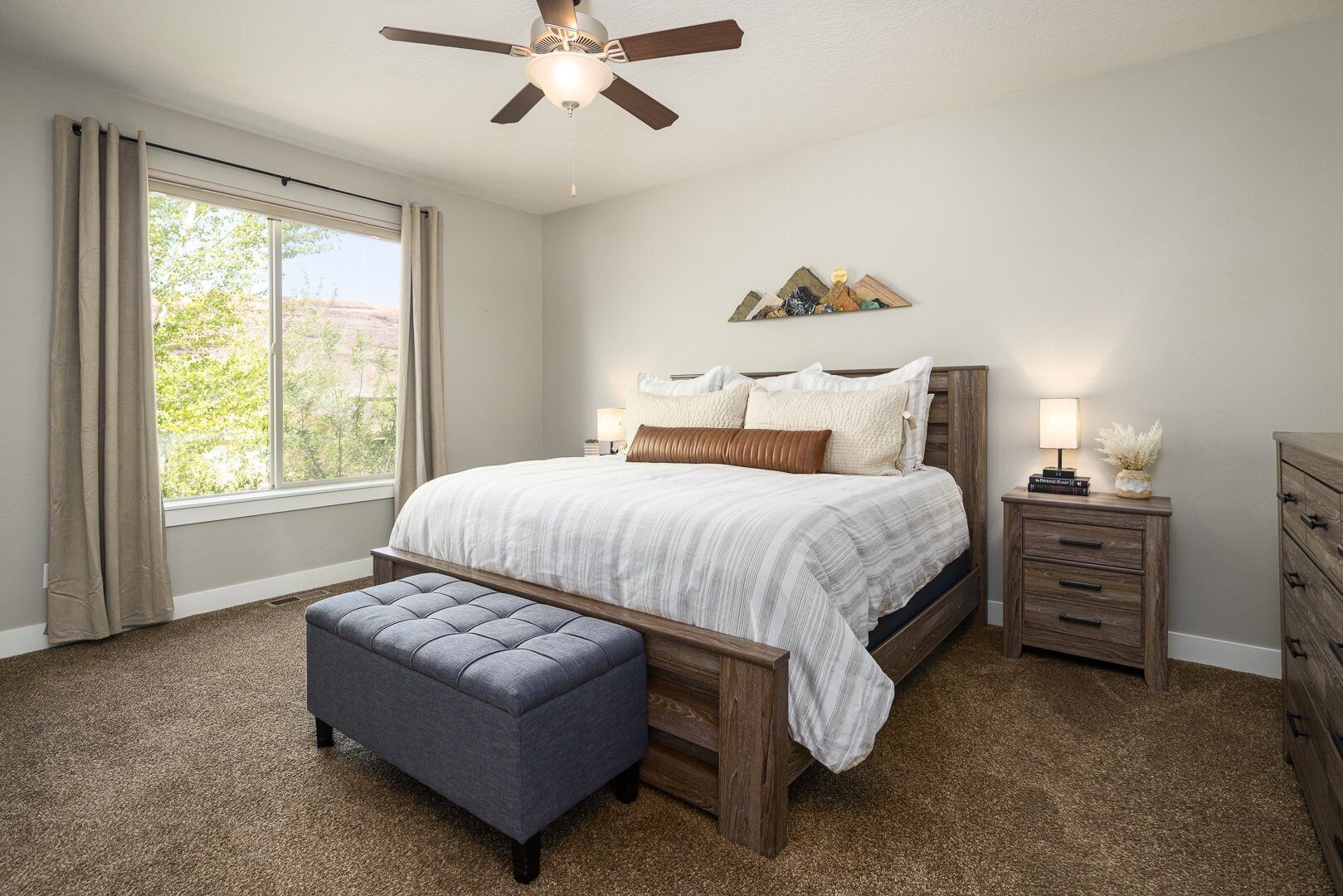 A bedroom with a bed, a bench, a nightstand, and a dresser.