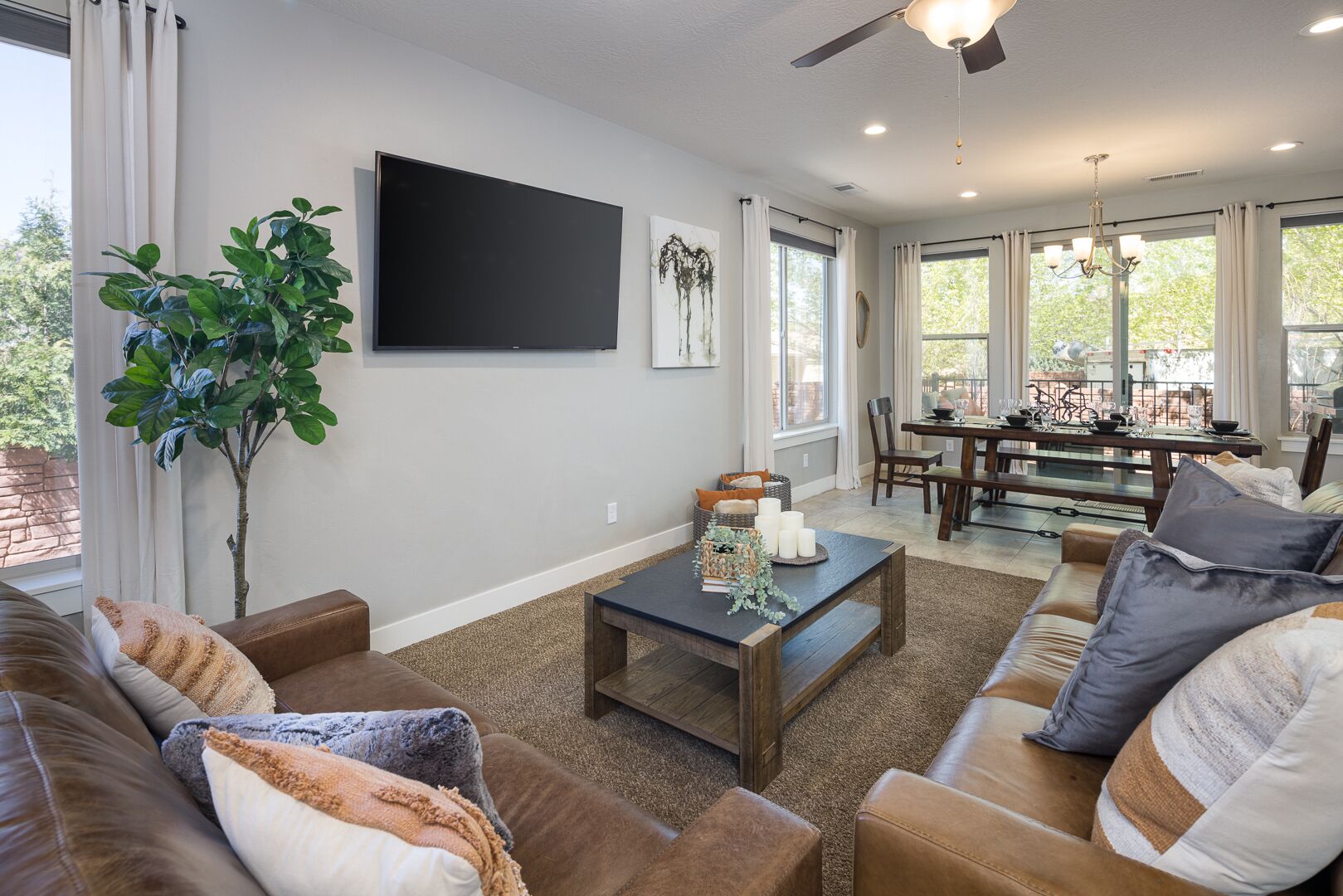 A living room with a large TV, a dining area, and a view of the outdoors.