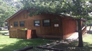 A wooden cabin with a small porch, a fenced yard, and a sign indicating it is private property. - Rio Cancion on Guadalupe Cabin 2 (New Braunfels)