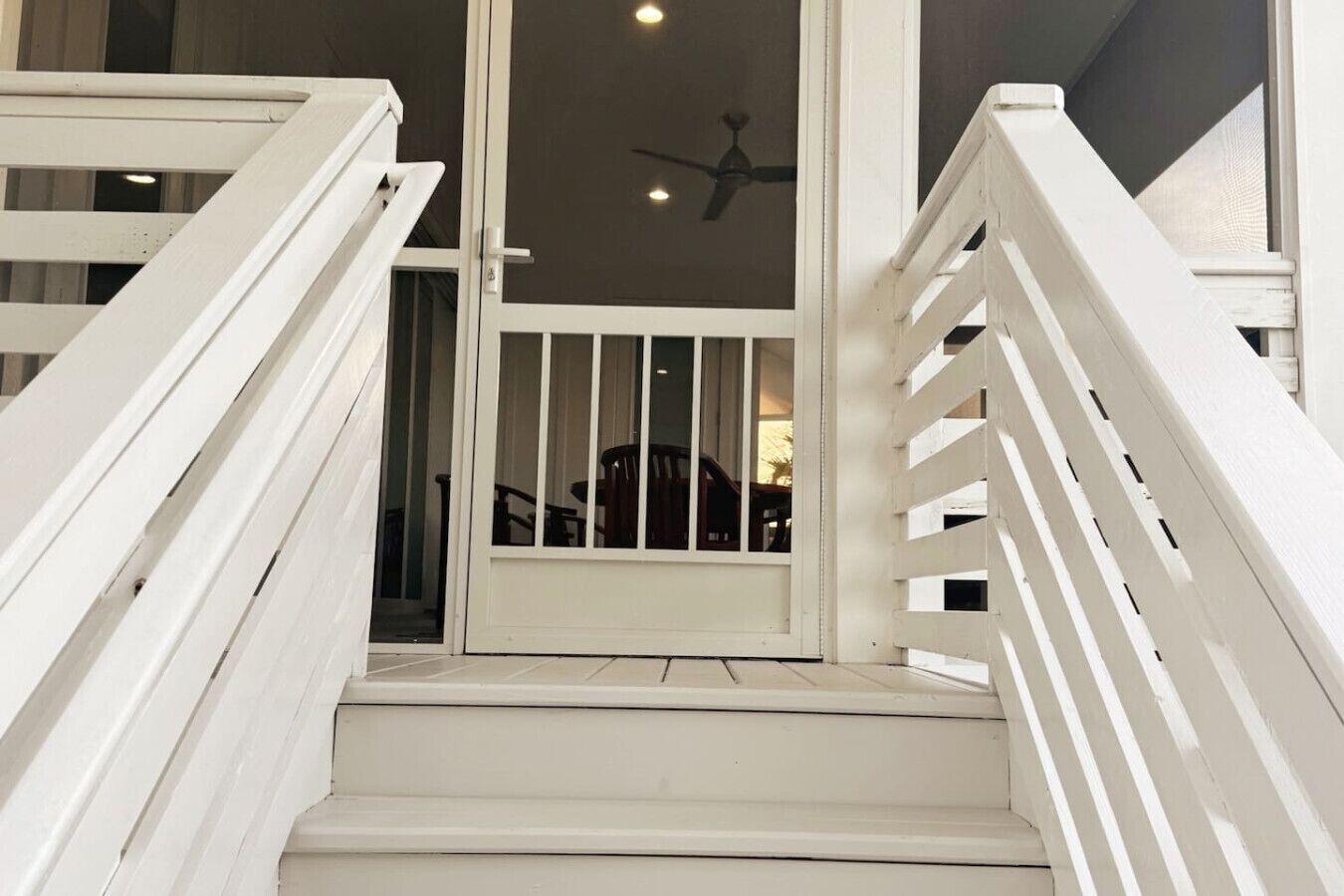 A white staircase with a glass door leading to a room.