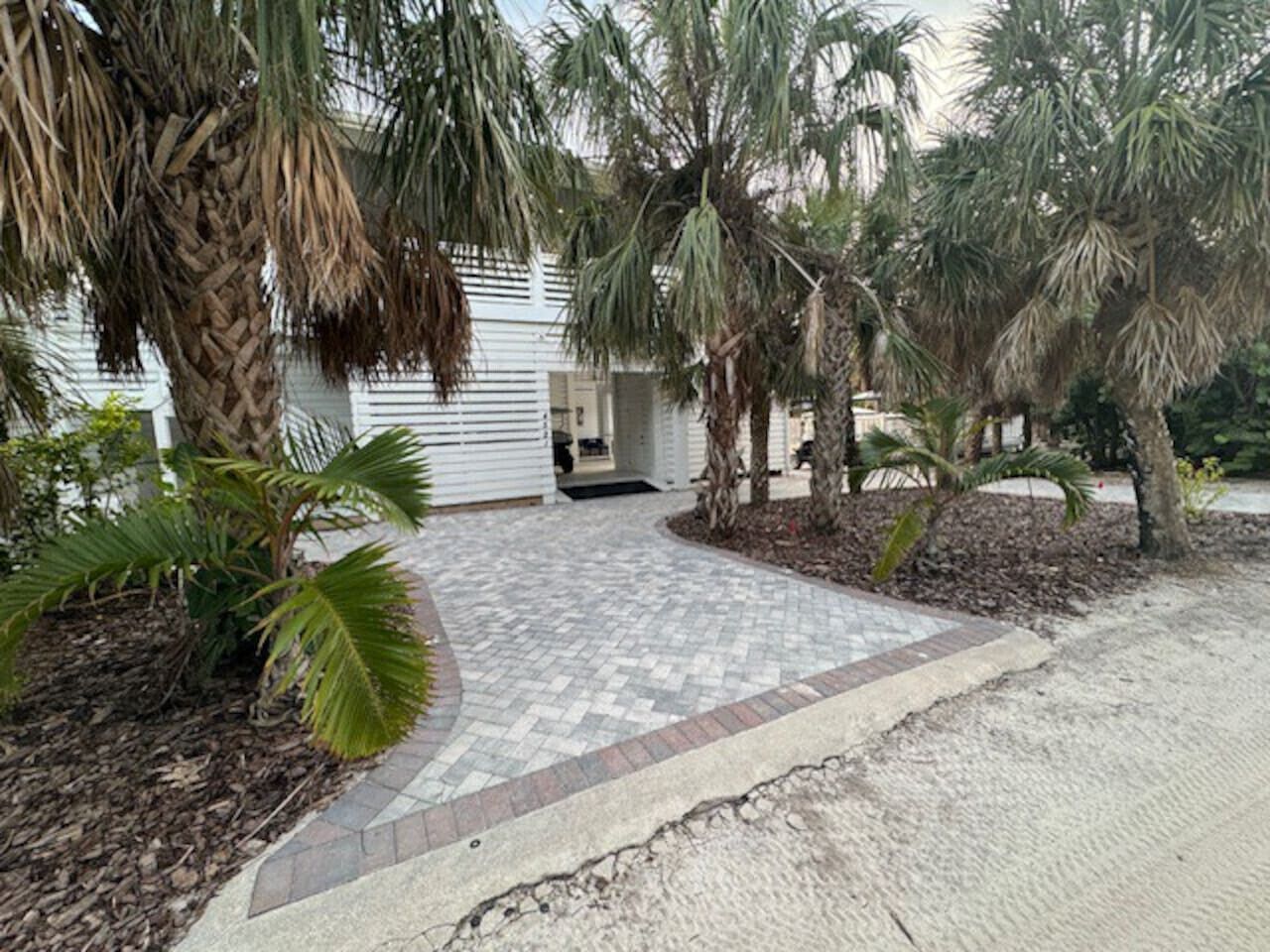 A paved walkway leading to a building with a white exterior and a covered entrance.