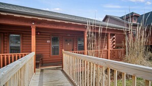 A wooden cabin with a porch and a wooden deck leading to the entrance. - Rustic Studio Cabin with King Bed and Jacuzzi Tub (Branson)