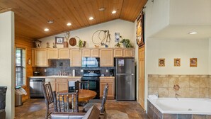 A kitchen with wooden cabinets, a dining table, and a built-in oven. - Rustic Studio Cabin with King Bed and Jacuzzi Tub (Branson)