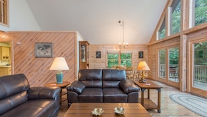 Un salon chaleureux avec une cheminée, des canapés en cuir et un plafond en bois.