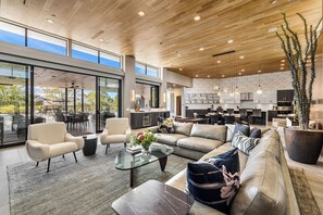 A spacious living area with a large sofa, a coffee table, and a dining area with chairs.