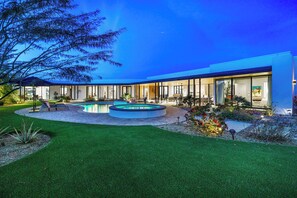 A modern house with a swimming pool, a patio, and a well-maintained lawn.