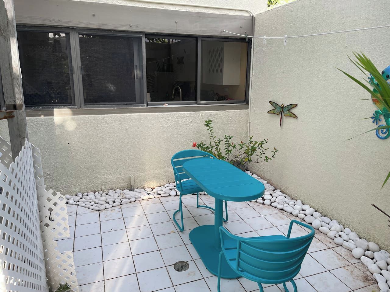 Une terrasse avec une table et des chaises, une fenêtre et un mur décoratif.