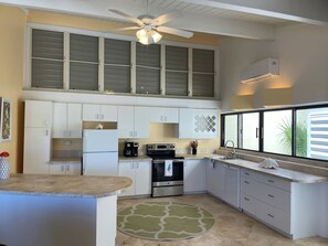 A kitchen with white cabinets, a stainless steel oven, a coffee maker, and a window with blinds.