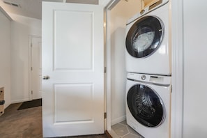 A laundry room with two stacked front-loading washing machines and a white door.